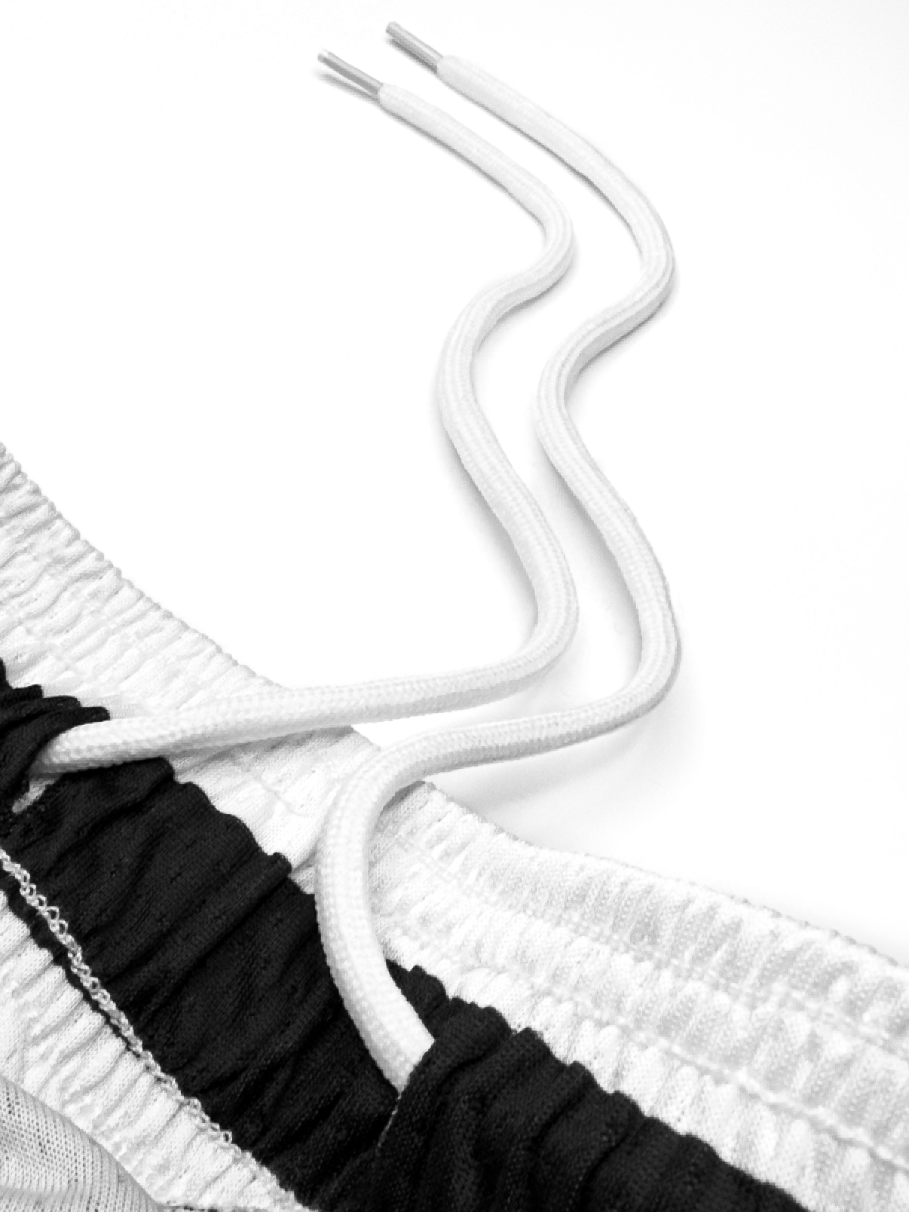 Close-up of a black and white textured fabric with a white cord.